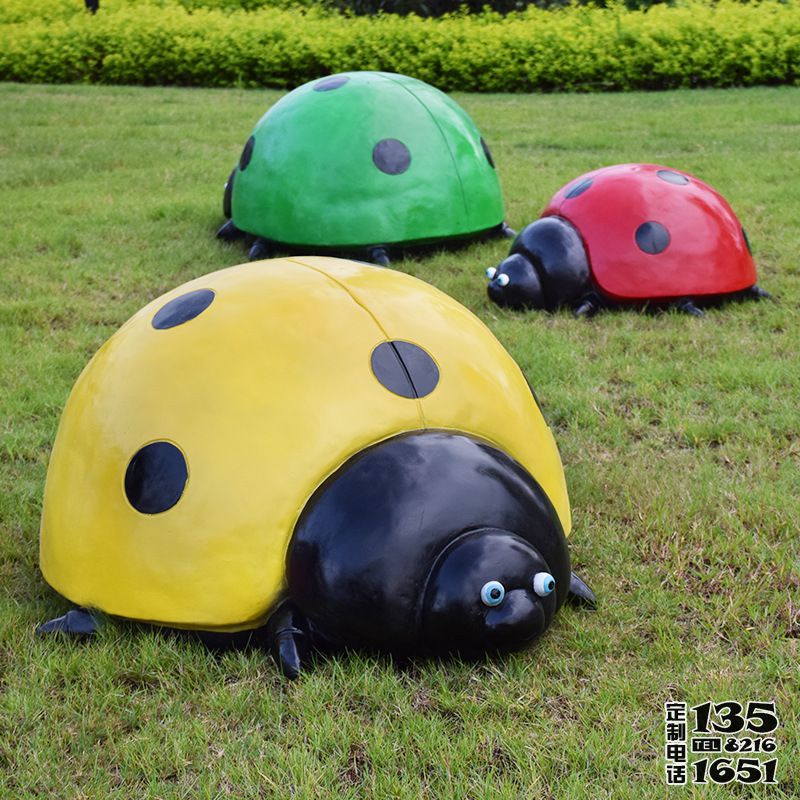 草地上擺放的三只不同顏色的玻璃鋼彩繪七星瓢蟲雕塑